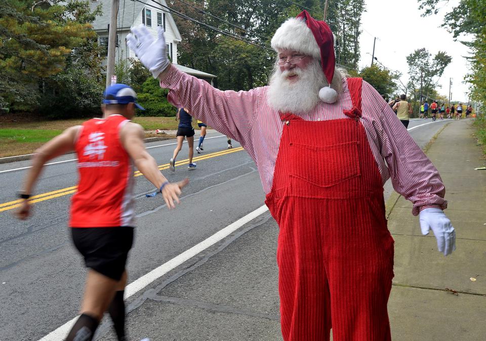 Santa Claus, (Jim Scott, of Natick) cheers on runners in Natick during the running of the 125th Boston Marathon, Oct. 11, 2021.