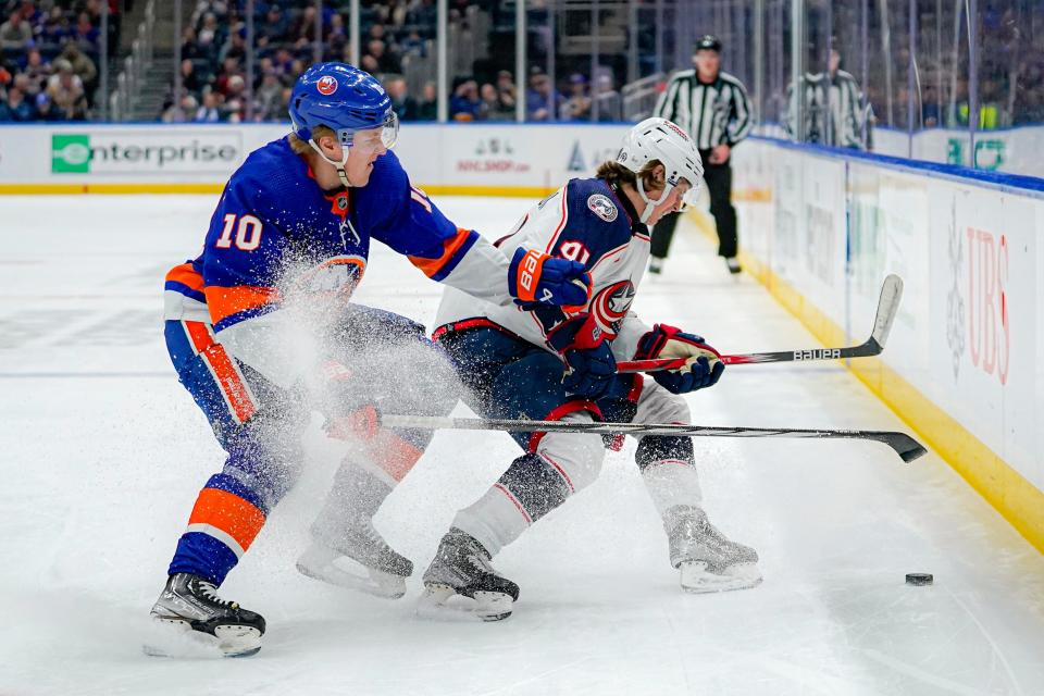 New York Islanders right wing Simon Holmstrom (10) and Columbus Blue Jackets center Kent Johnson, front right, battle for the puck during the third period of an NHL hockey game in Elmont, N.Y., Thursday, Dec. 7, 2023. (AP Photo/Peter K. Afriyie)