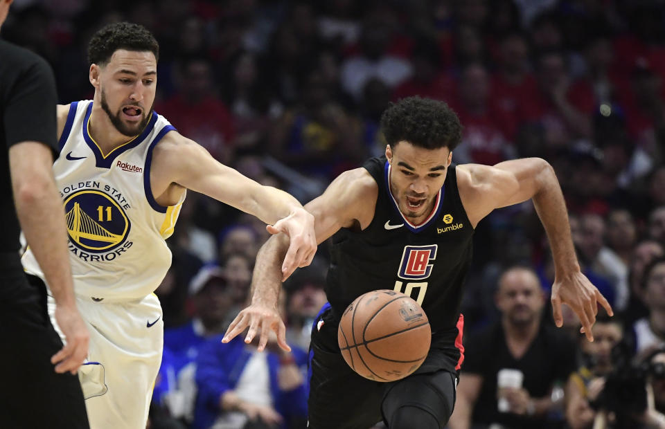 Golden State Warriors guard Klay Thompson, left, and Los Angeles Clippers guard Jerome Robinson reach for a loose ball during the first half in Game 4 of a first-round NBA basketball playoff series Sunday, April 21, 2019, in Los Angeles. (AP Photo/Mark J. Terrill)