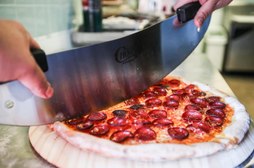 Executive chef Bryce Montesa slices a pepperoni pizza in the kitchen of Hop Atomica. Feb. 20, 2024