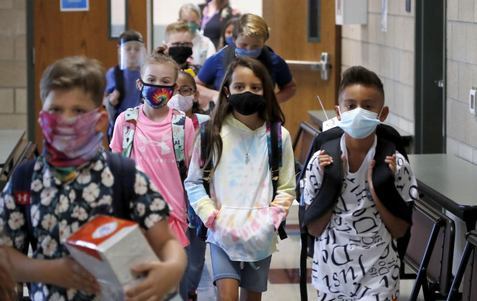 Wearing masks to prevent the spread of Covid, elementary school students walk to classes to begin their school day in Godley, Texas, on Aug. 5, 2020. (LM Otero / AP)