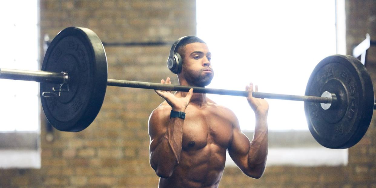 man lifting barbell wearing headphones