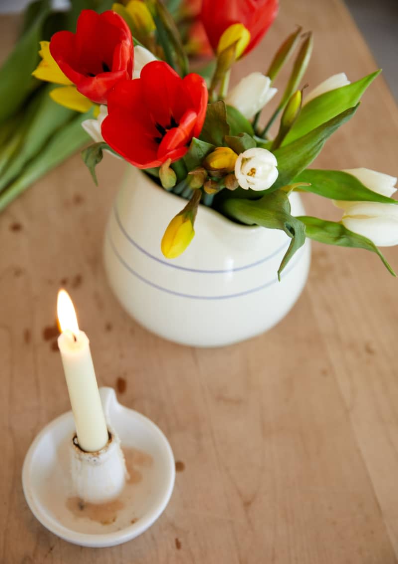 Decorative flowers sit in a vase next to a lit candle