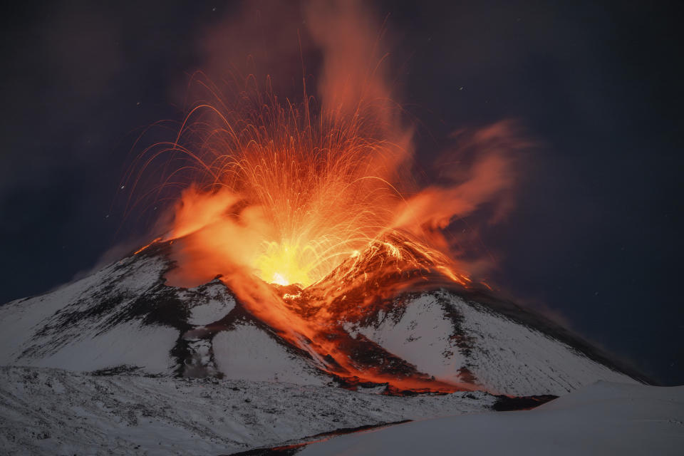 Lava erupts from snow-covered Mount Etna volcano, Sicily, Italy, early Saturday, Nov. 25, 2023. Europe's most active volcano remains active scattering ashes around a vastly populated area on its slopes. (AP Photo/Etnawalk, Giuseppe Di Stefano)