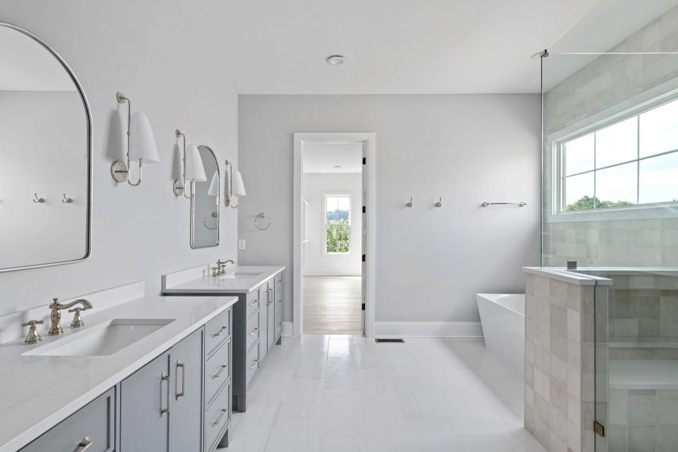 The en suite bathroom features double vanities, a large tub, and a standing shower.