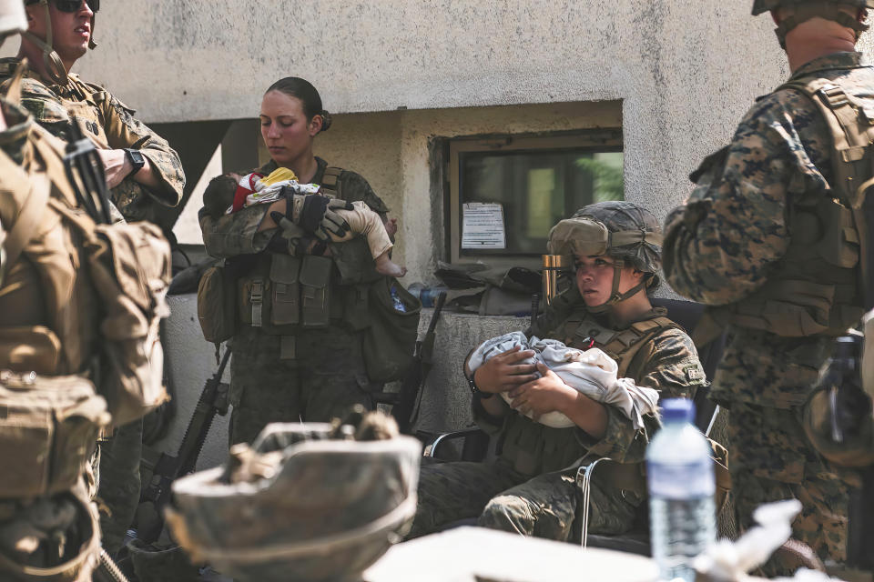 In this Aug. 20, 2021, image provided by the U.S. Marine Corps, Marines assigned to the 24th Marine Expeditionary Unit (MEU), including Sgt. Nicole Gee, standing at left, calm infants during an evacuation at Hamid Karzai International Airport in Kabul, Afghanistan. Officials said Aug. 28, that Gee of Sacramento, Calif., was one of the Marines killed in Thursday's bombing at the airport. (Sgt. Isaiah Campbell/U.S. Marine Corps via AP)