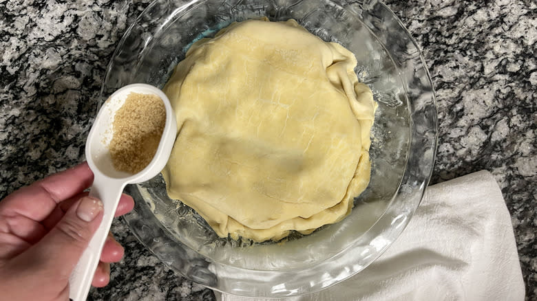 hand sprinkling sugar on unbaked pie