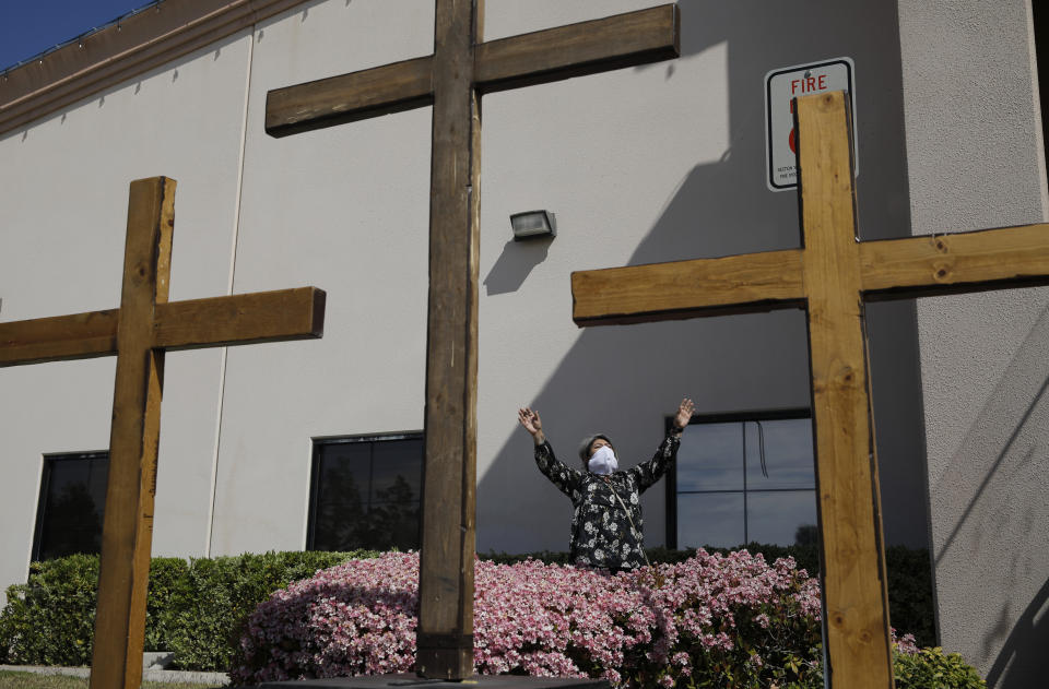 FILE - In this April 12, 2020, file photo, Norma Urrabazo prays while wearing a facemask before speaking at an Easter drive-in service at the International Church of Las Vegas in Las Vegas. The Trump administration is warning Nevada's Democratic governor that his plan for reopening the state during recovery from the coronavirus fails to treat religious and secular gatherings equally. In a letter sent Monday, May 25, 2020, to Gov. Steve Sisolak, the head of the Justice Department's civil rights division took issue with the first phase of Sisolak's guidelines for restarting economic and social activity in the state. (AP Photo/John Locher, File)