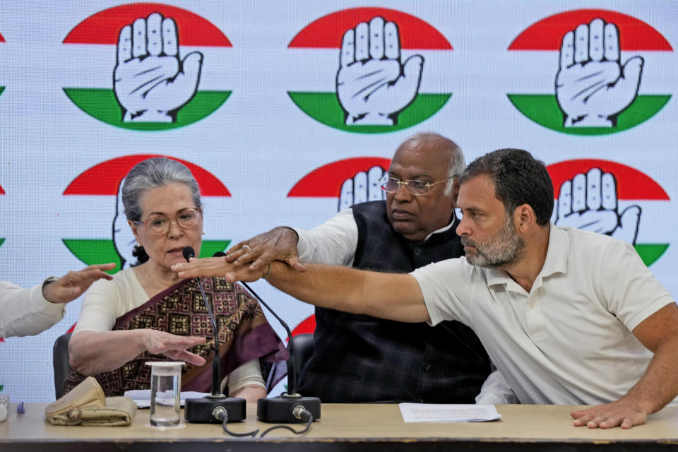 Congress party president Mallikarjun Kharge, center, and Rahul Gandhi, right, adjust the microphones for senior party leader Sonia Gandhi to speak during a press conference at their party headquarters in New Delhi, India, Thursday, March 21, 2024. (AP Photo/Manish Swarup)