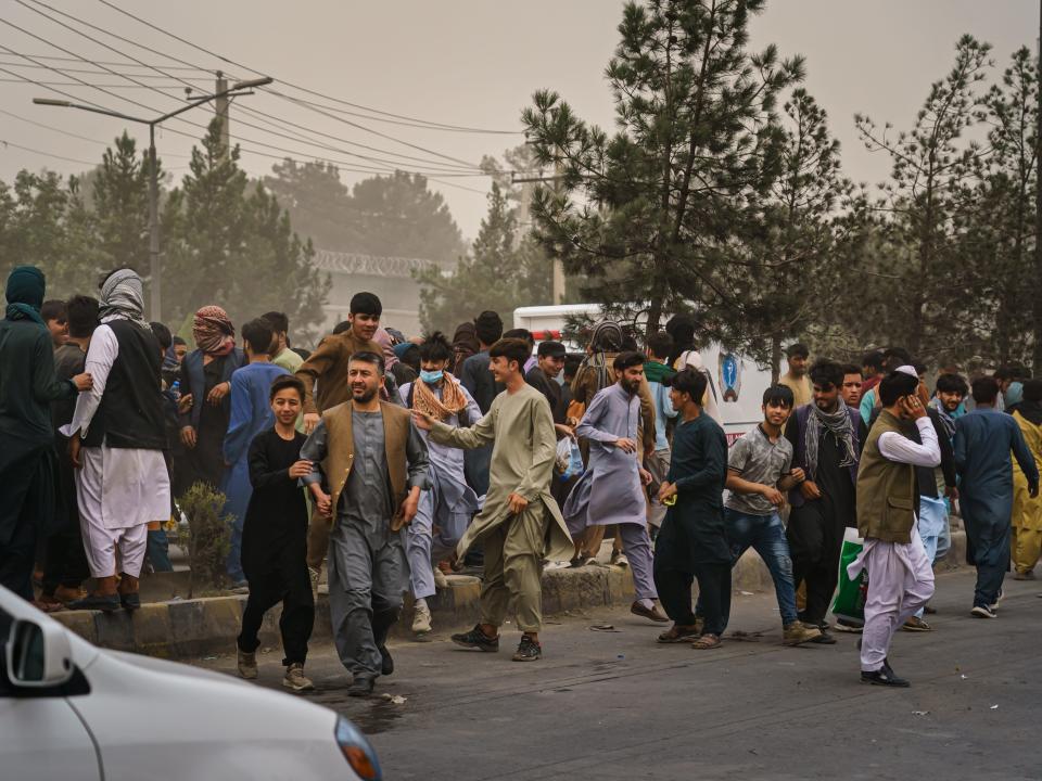 Afghans run away after Taliban fighters use guns fire, whips, sticks and sharp objects to maintain crowd control