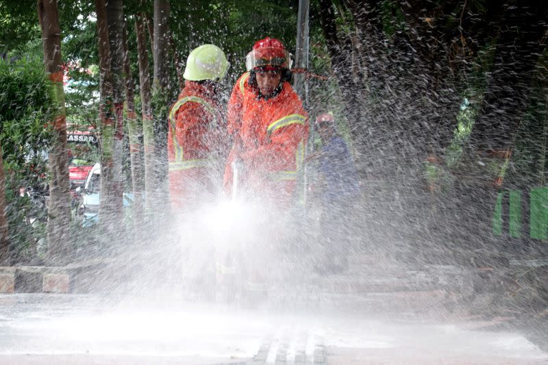 Firefighters spray disinfectant on the road, to prevent the spread of coronavirus disease (COVID-19) in Makassar