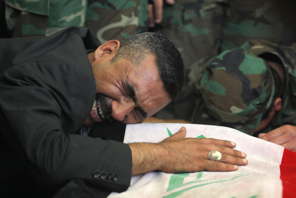 FILE - In this file photo taken Saturday, April 26, 2014, a man mourns over the flag-draped coffin of his son during a funeral procession for five militia members of a Shiite group, Asaib Ahl al-Haq, or League of the Righteous, in the Shiite holy city of Najaf, 100 miles (160 kilometers) south of Baghdad, Iraq. As parliamentary elections are held Wednesday, April 30, more than two years after the withdrawal of U.S. troops, Baghdad is once again a city gripped by fear and scarred by violence. (AP Photo/Jaber al-Helo, File)