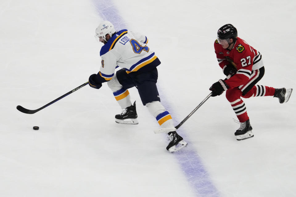 St. Louis Blues defenseman Nick Leddy, left, chases the puck past Chicago Blackhawks left wing Lukas Reichel during the second period of an NHL hockey game in Chicago, Sunday, Nov. 26, 2023. (AP Photo/Nam Y. Huh)