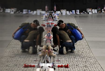 Visitors examine items left at the base of the Vietnam Veterans Memorial in Washington, in this May 27, 2007 file photo. REUTERS/Jonathan Ernst/Files