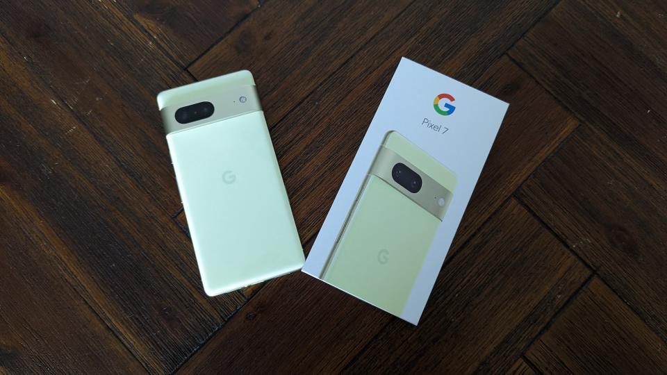 A yellow Google Pixel 7 with its packaging on a brown table.