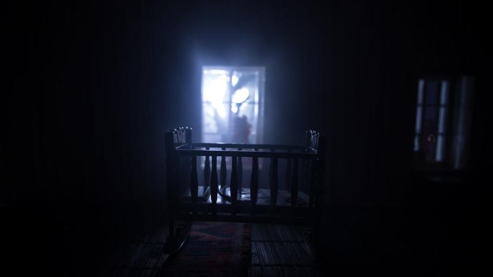 old creepy eerie baby crib near window in dark room scary baby silhouette in dark a realistic dollhouse living room with furniture and window at night selective focus