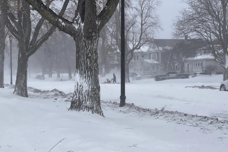 A person clears snow from the sidewalk during a snowstorm on Saturday, Dec. 24, 2022 in Buffalo, N.Y. A battering winter storm has knocked out power to 1.7 million homes and businesses across the United States on Saturday. Gov. Kathy Hochul said Saturday that the the Buffalo Niagara International Airport will be closed through Monday morning, some roads would be closed through Christmas day and almost every fire truck in Buffalo was stranded in the snow. (AP Photo/Carolyn Thompson)