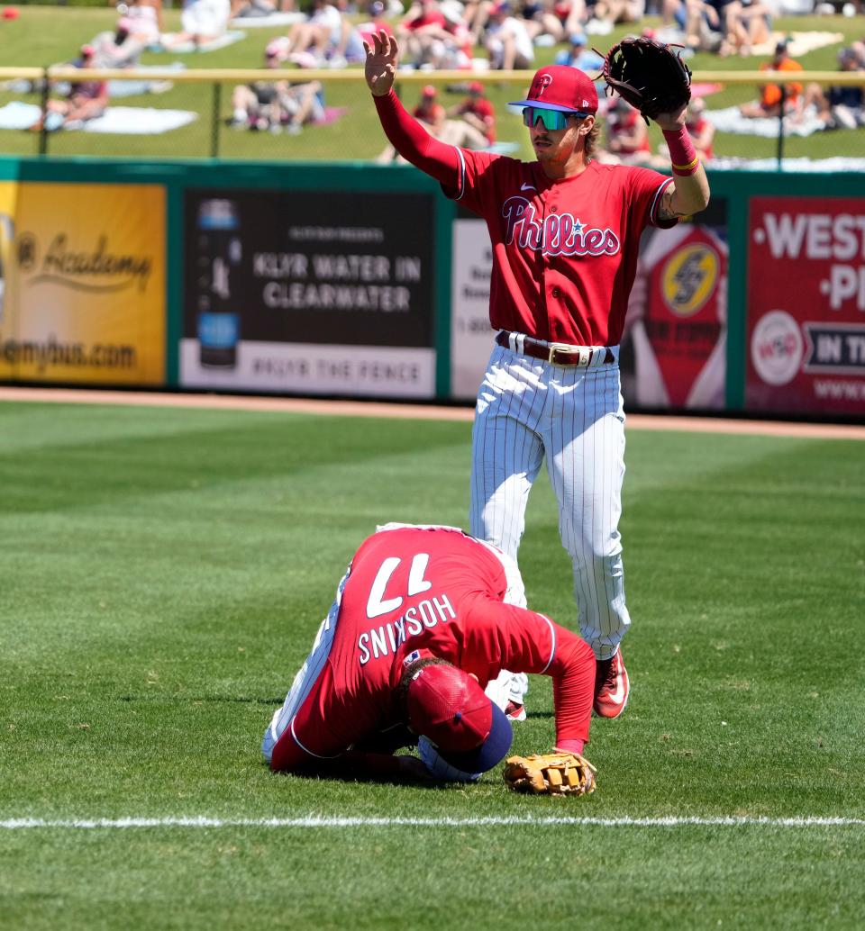 Philadelphia Phillies first baseman Rhys Hoskins (17) falls to the ground as right fielder Nick Castellanos (9) motions for a time out after Hoskins was inured trying to field a ball hit by the Detroit Tigers during the first inning at BayCare Ballpark, May 23, 2023 in Clearwater, Florida.