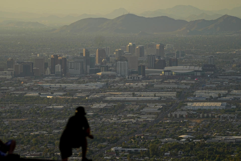 FILE - A man overlooks downtown Phoenix at sunset atop South Mountain, Sunday, July 30, 2023. Phoenix hit its 31st consecutive day of at least 110 degrees Fahrenheit (43.3 Celsius). Record setting temperatures are expected Saturday, Aug. 19, across Texas as the southwestern U.S. continues to bake during a scorching summer. (AP Photo/Matt York, File)