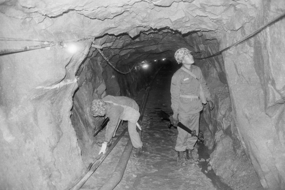 A black and white photo of two South Korean soldiers examining tunnels built by North Korea in the DMZ in Korea.