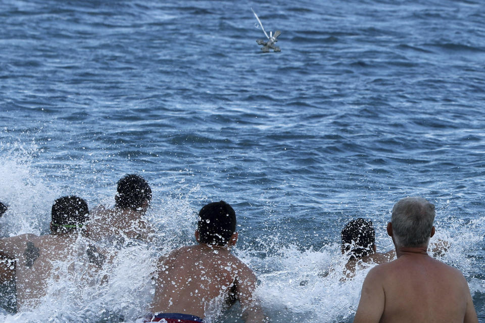 Swimmers try to catch the cross as it is thrown by an Orthodox priest into the water, during an epiphany ceremony to bless the sea at Famagousta in the abandoned city in the Turkish occupied area at north part of the eastern Mediterranean divided island of Cyprus, Monday, Jan. 6, 2020. Many Orthodox Christian faithful attended the Epiphany Day blessing of the waters in Famagusta in Cyprus', the fifth time the ceremony has taken place since 1974 when the small island nation was cleaved along ethnic lines. (AP Photo/Petros Karadjias)