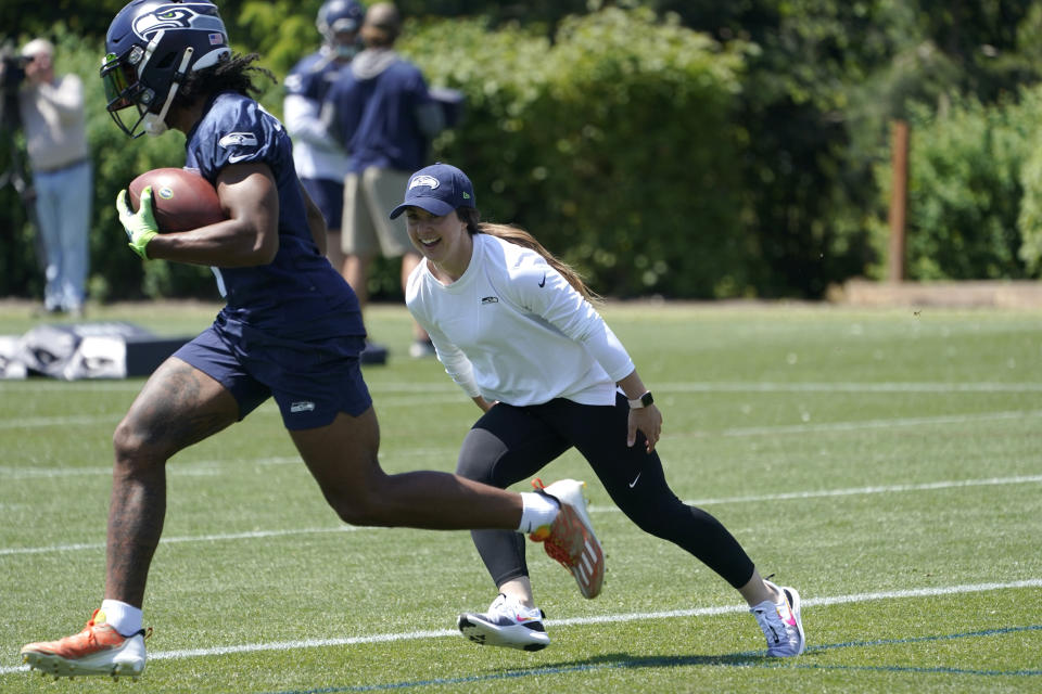 Amanda Ruller, who is currently working as an assistant running backs coach for the NFL football Seattle Seahawks through the league's Bill Walsh Diversity Fellowship program, runs a drill with wide receiver Dee Eskridge during NFL football practice on May 31, 2022, in Renton, Wash. Ruller's job is scheduled to run through the Seahawks' second preseason game in August. (AP Photo/Ted S. Warren)