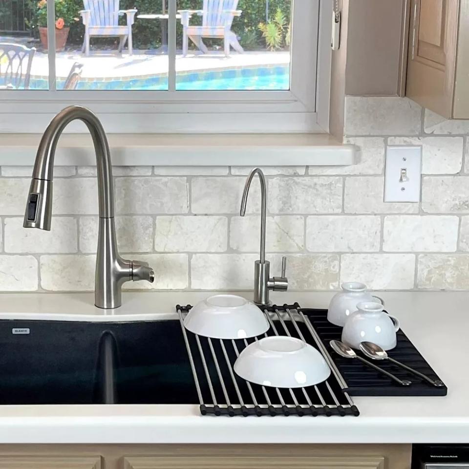 a drying rack hanging over a sink with dishes drying on it