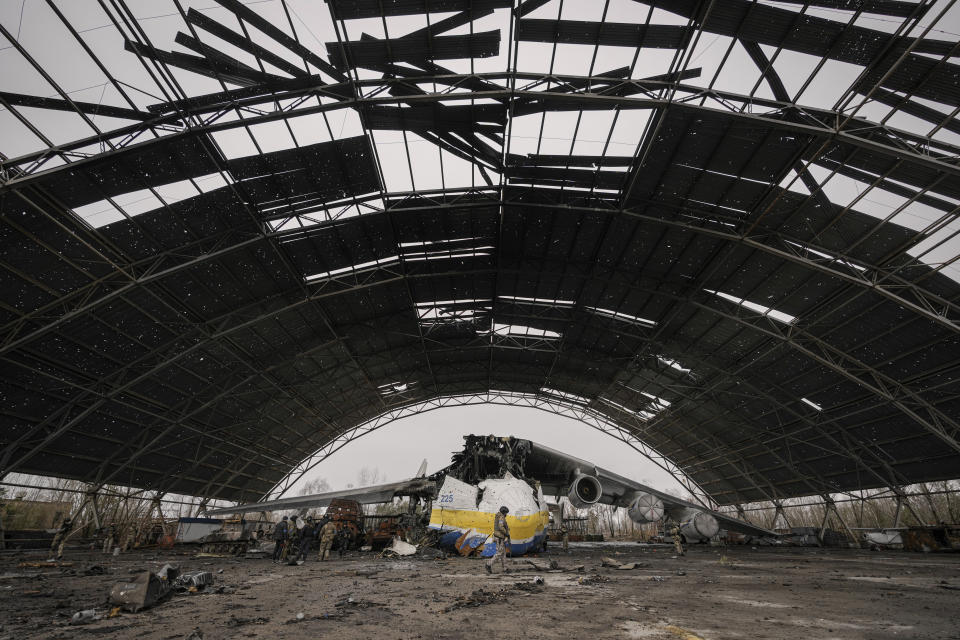 A Ukrainian serviceman walks by the Antonov An-225 Mriya aircraft destroyed during fighting between Russian and Ukrainian forces on the Antonov airport in Hostomel, Ukraine, Saturday, April 2, 2022. (AP Photo/Vadim Ghirda)