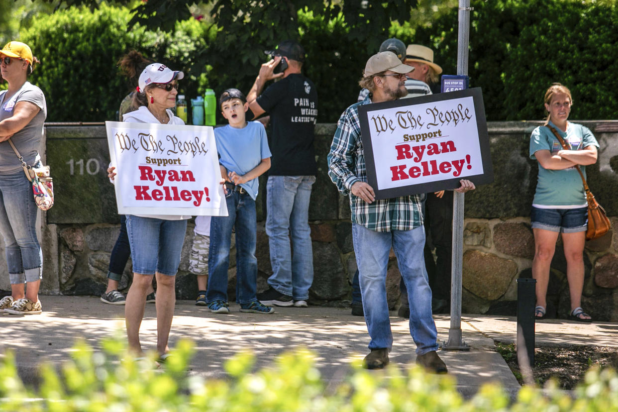 Image: Supporters of Michigan gubernatorial candidate Ryan Kelly hold up signs as traffic passes by on Michigan Street while waiting for him to come out of the U.S. District Court in Grand Rapids, Mich., on June 9, 2022. (Daniel Shular / The Grand Rapids Press via AP file)