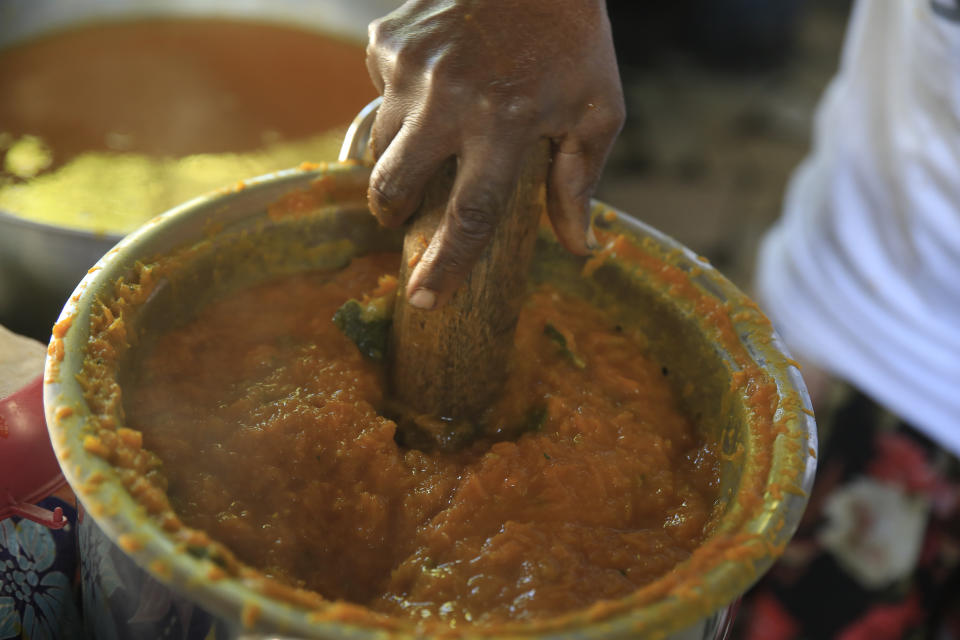 Rose Felicien, 62, mashes baked pumpkin while preparing traditional soup joumou, in the Delmas district of Port-au-Prince, Haiti, Sunday, Feb. 5, 2023. Made of pumpkin, beef, carrots, cabbage, ingredients produced on the island, soup joumou is a cultural staple in Haiti. (AP Photo/Odelyn Joseph)