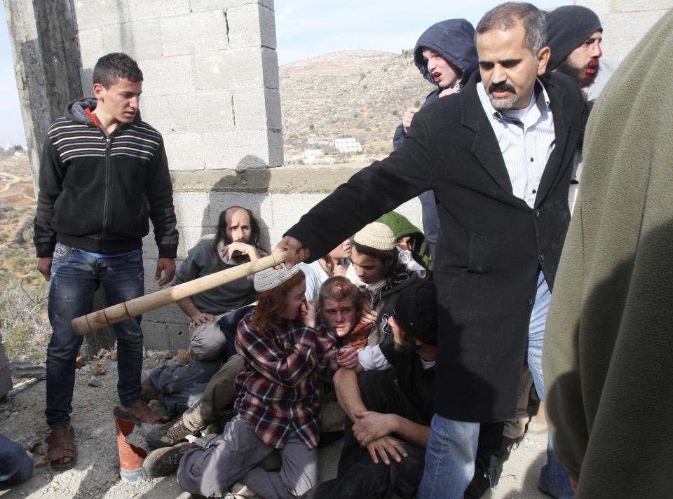 A Palestinian villager tries to protect injured Jewish settlers after they were detained near Nablus