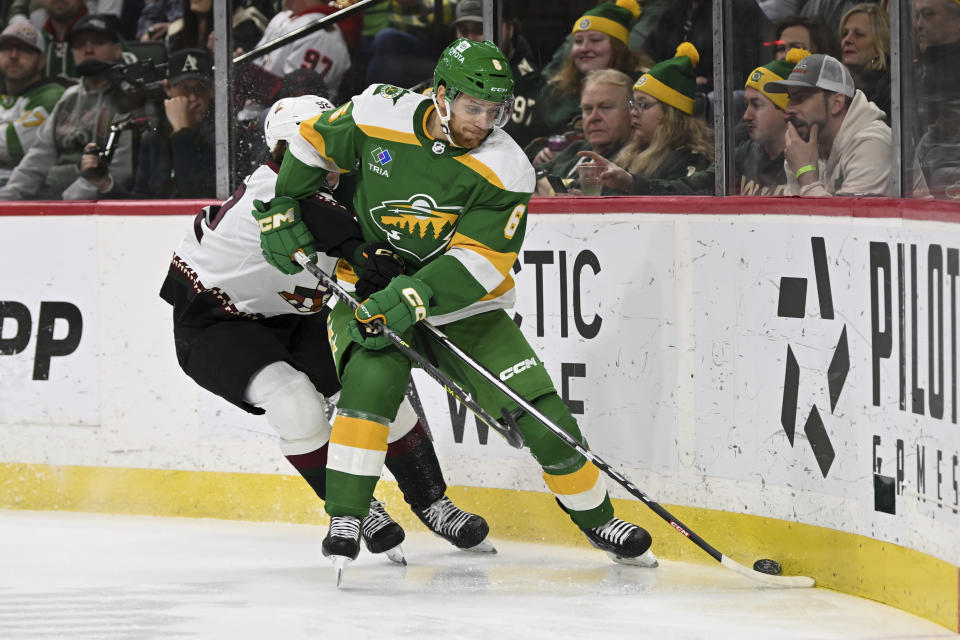 Minnesota Wild defenseman Dakota Mermis, right, battles with Arizona Coyotes center Logan Cooley, left, for control of the puck during the second period of an NHL hockey game Saturday, Jan. 13, 2024, in St. Paul, Minn. (AP Photo/Craig Lassig)