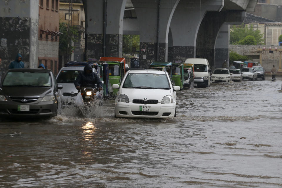 A motorcyclist and car drivers drive through a flooded road caused by heavy rain in Peshawar, Pakistan, Monday, April 15, 2024. Lightening and heavy rains killed dozens of people, mostly farmers, across Pakistan in the past three days, officials said Monday, as authorities declared a state of emergency in the country's southwest following an overnight rainfall to avoid any further casualties and damages. (AP Photo/Muhammad Sajjad)