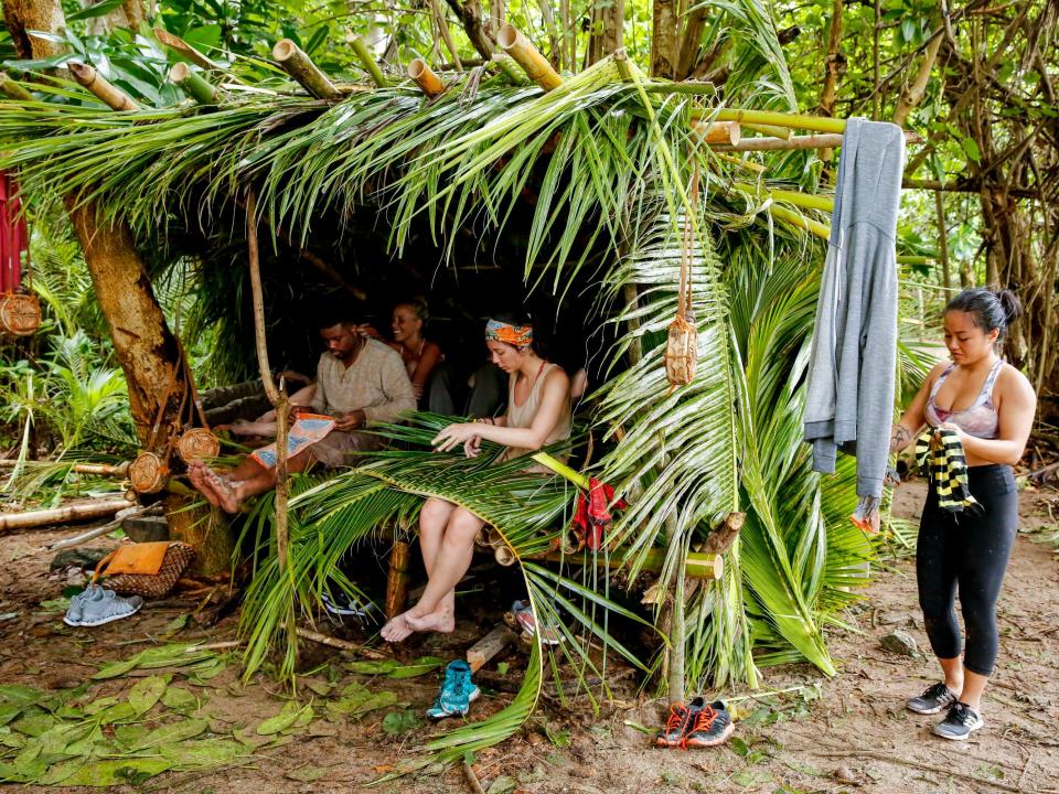 Davie Rickenbacker and others at camping sitting in a palm leaf and bamboo hurt on "Survivor"