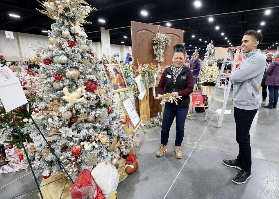 Afu Fiefia, right, watches Becky Yamasaki, Festival of Trees executive board member, put finishing touches on a tree decorated in honor of Fiefia at the 53rd annual Festival of Trees to benefit Intermountain Primary Children’s Hospital patients, at the Mountain America Expo Center in Sandy on Monday. Fiefia, 17, was diagnosed with Ewing sarcoma in 2021 and has been in remission for eight months.