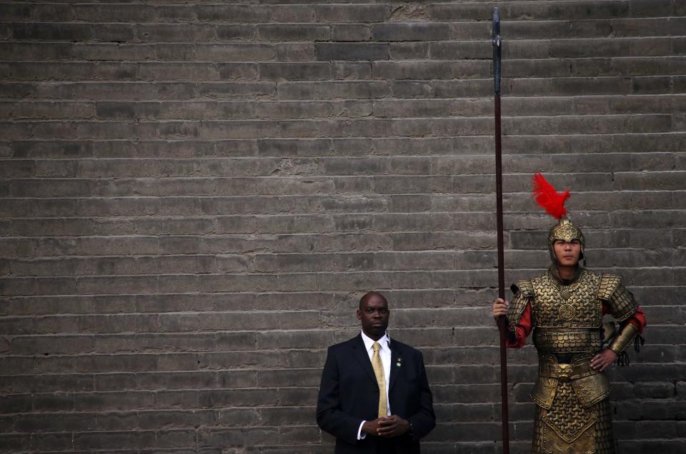 A security guard of U.S. first lady Michelle Obama stands beside a man wearing a Chinese ancient warrior costume during Obama's visit at the City Wall in Xi'an, Shaanxi province, March 24, 2014. (REUTERS/Petar Kujundzic)