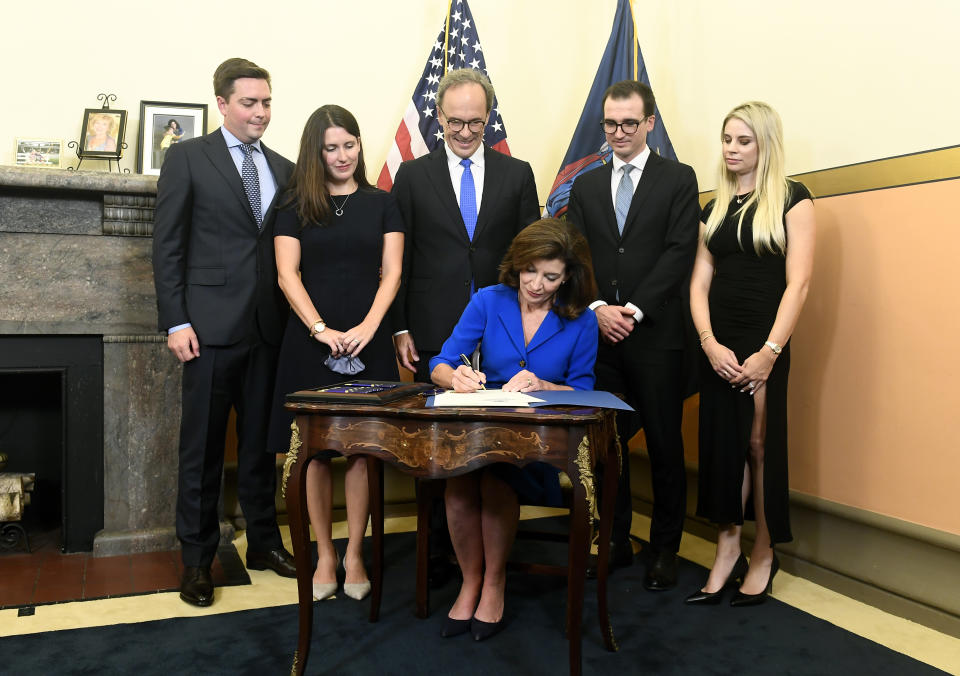 From left, family members Katie Hochul and Matt Gloudeman, Bill Hochul, center, and Will and Christina Hochul watch as Kathy Hochul, the first woman to be New York's governor, signs documents during a swearing-in ceremony in the Red Room at the state Capitol, early Tuesday, Aug. 24, 2021, in Albany, N.Y. (AP Photo/Hans Pennink, Pool)