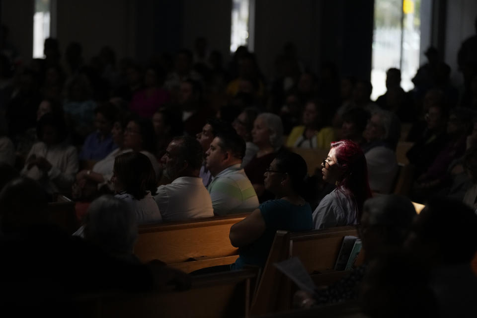 Cinthya Benavides, lit by a beam of light from a skylight, attends Mass at St. Agatha Catholic Church, a hub of Miami's Nicaraguan community, Sunday, Nov. 5, 2023, in Miami. Moves by the Nicaraguan government against young protesters and the church, where college student Benavides was active in youth ministry, pushed her to leave Nicaragua – fleeing her house with only her passport, phone and laptop as police knocked on the front door. (AP Photo/Rebecca Blackwell)