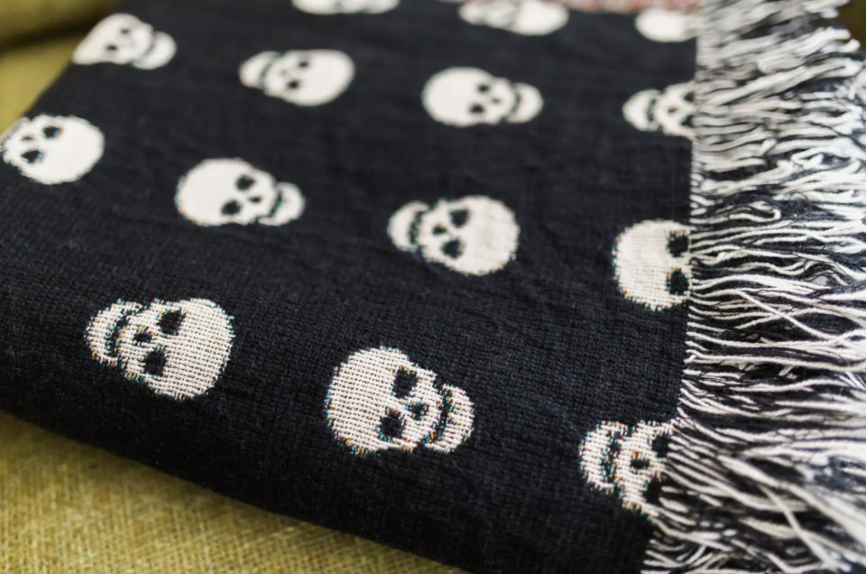 black and white Skull Throw Blanket on green sofa