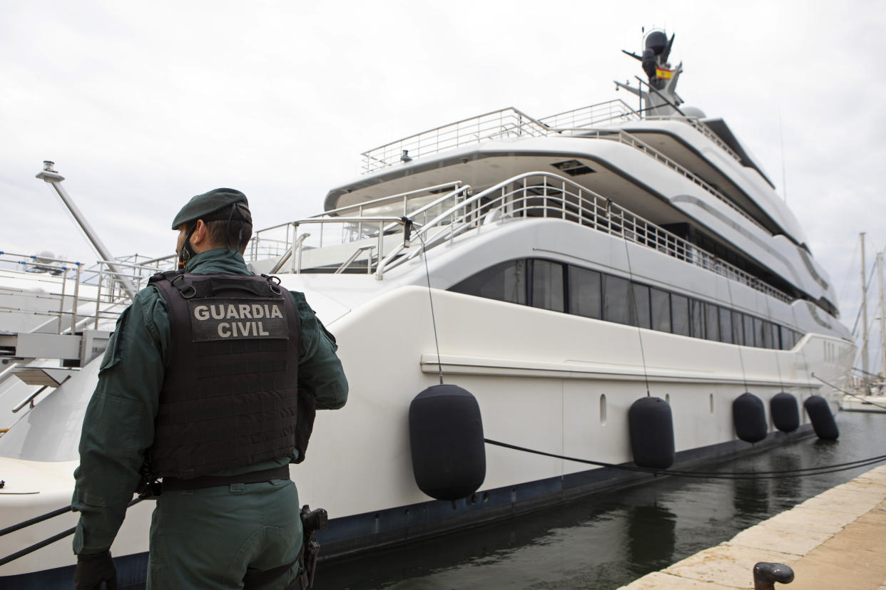 A member of the Spanish Civil Guard stands by a huge white yacht.