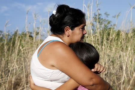 A woman cries while embracing her daughter before sending her to Colombia with a Colombian policeman, through the Tachira River at San Antonio in Tachira state, Venezuela, August 27, 2015. REUTERS/Carlos Garcia Rawlins