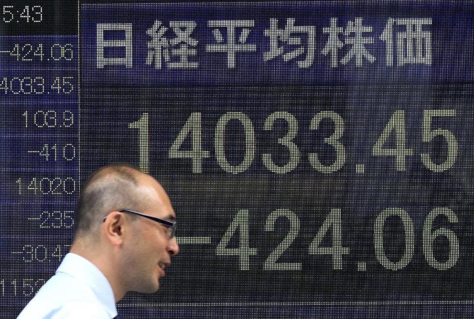 A man walks by an electronic stock board of a securities firm in Tokyo, Wednesday, May 7, 2014. A dismal day on Wall Street spilled over into Asian trading Wednesday as jitters over the valuations of technology companies contributed to a sharp drop in Japan's benchmark. The Nikkei 225 stock index fell 2.3 percent to 14,120.25. Japanese markets were closed the previous two days for public holidays. (AP Photo/Eugene Hoshiko)