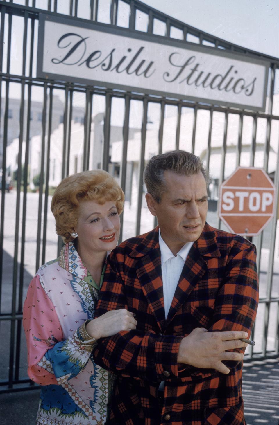 Ball and Arnaz pose next to the gates of their Desilu Studios in L.A. in August 1958.