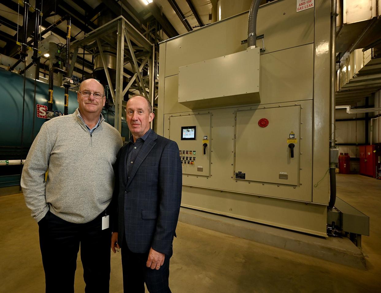 Bob Doherty, facilities manager, and Patrick Redington, general manager, stand before Saint-Gobain's new $22 million machine, called the "powerhouse," that will power Saint-Gobain's entire Worcester site and will cut the site's carbon emissions by 50%.