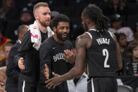 Brooklyn Nets guard Dzanan Musa, left, and /guard Kyrie Irving, center, greet forward Taurean Prince (2) as he comes into the bench during a timeout in the first half of an exhibition NBA basketball game against the Sesi/Franca Basketball Club, Friday, Oct. 4, 2019, in New York. (AP Photo/Mary Altaffer)