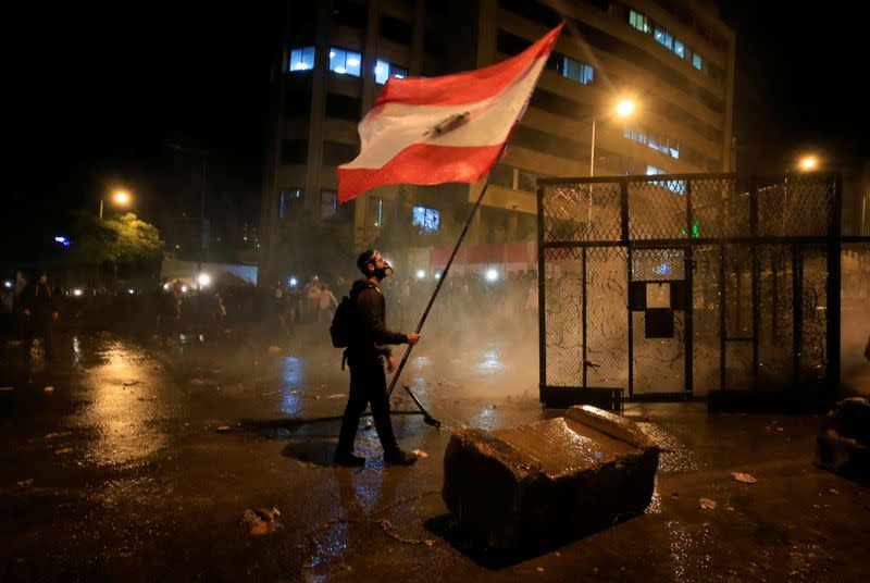 FILE PHOTO: A demonstrator holds the Lebanese flag during a protest against the newly formed government outside the government headquarters in downtown Beirut