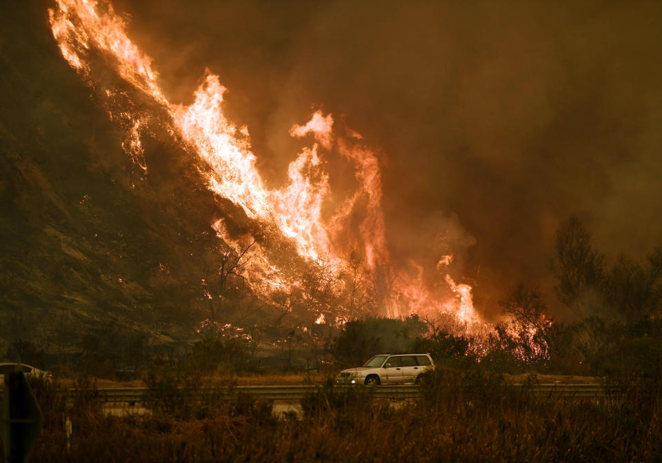 Vehicles pass beside a wall of flames on the 101 highway during&nbsp;a wildfire near Ventura, California, on Dec.&nbsp;6, 2017.