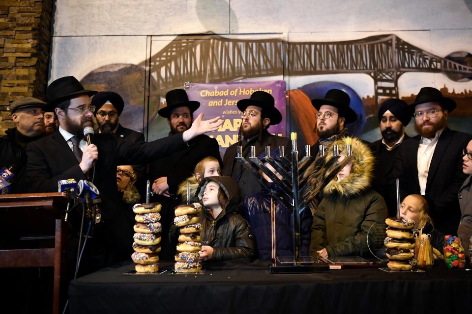 Rabbi Moshe Schapiro, far left, leads the service before the menorah lighting in front of the Kosher deli where the anti-Semitic shooting killed three people within the deli on Sunday, Dec. 22, 2019, in Jersey City.