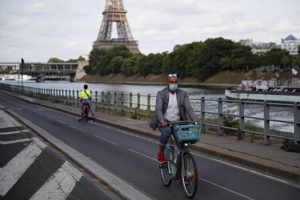 Parisians ride their bikes along the Seine river in Paris, Sunday, May 24, 2020 as France gradually lifts its COVID-19 lockdown. In the French capital this weekend, Parisians soaked up the sun along the embankments of the Seine River and lounged on ledges outside the Tuileries Gardens, still shuttered like all of the city's parks as the city gradually emerges from confinement. (AP Photo/Francois Mori)