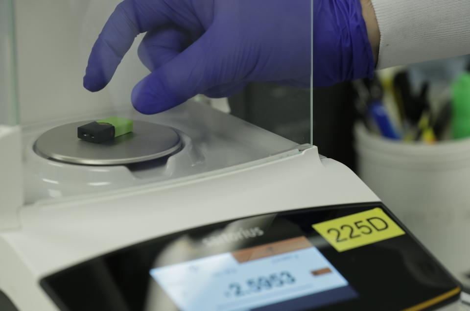 A Green Machine brand CBD vape pod is weighed during testing at Flora Research Laboratories in Grants Pass, Ore., on July 18, 2019. As part of an investigation into CBD vapes, The Associated Press commissioned the lab to test vape products purchased around the country, including seven Green Machine pods bought at stores in California, Florida and Maryland. Four of the Green Machine pods contained synthetic marijuana, a dangerous street drug commonly known as K2 or spice. (AP Photo/Ted Warren)